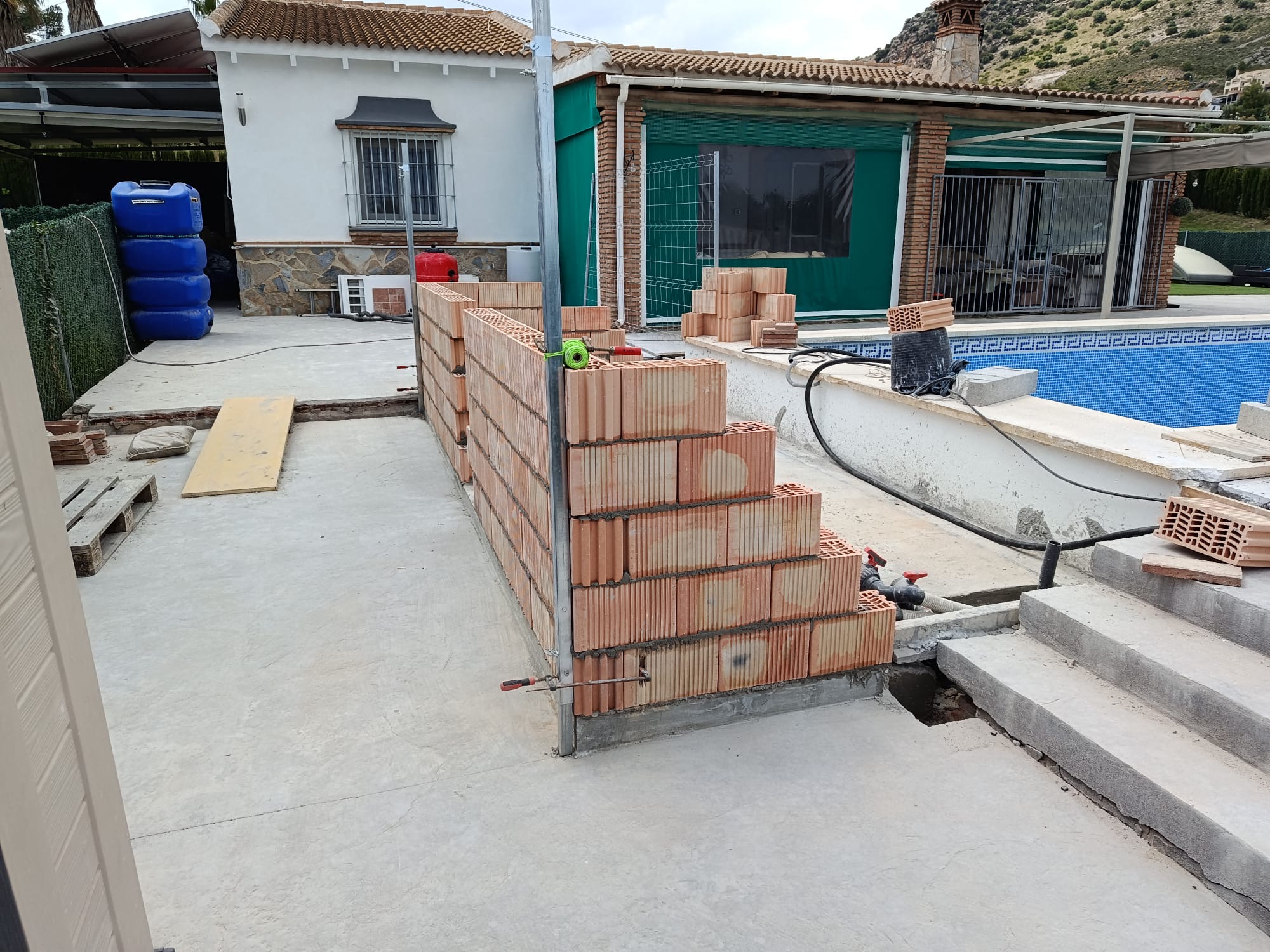 Brickwork under construction beside an outdoor swimming pool